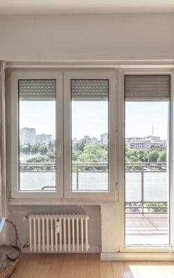 Large window of a room with an exit door to a terrace with views of an urban park